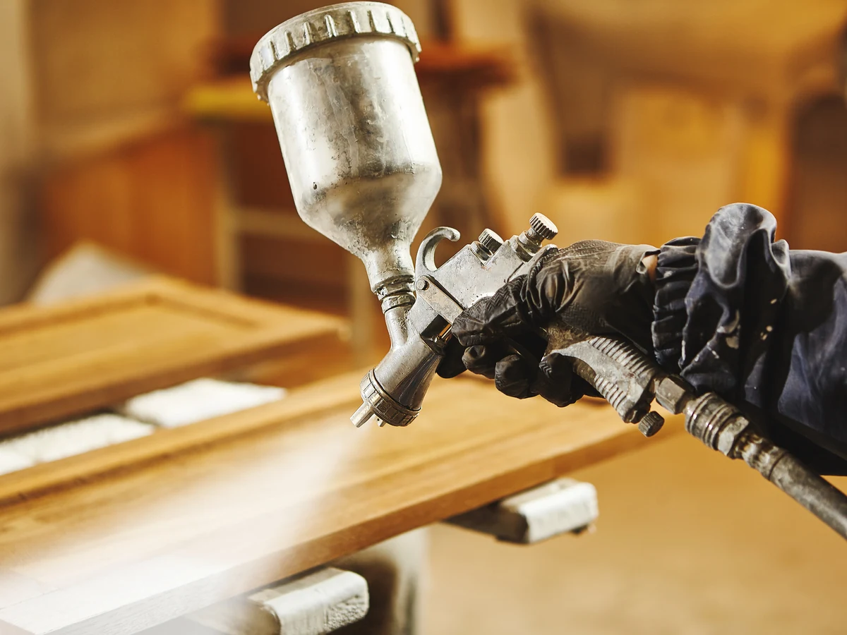 Painter applying specialist coating in Bath bathroom, close-up of hands with spray equipment