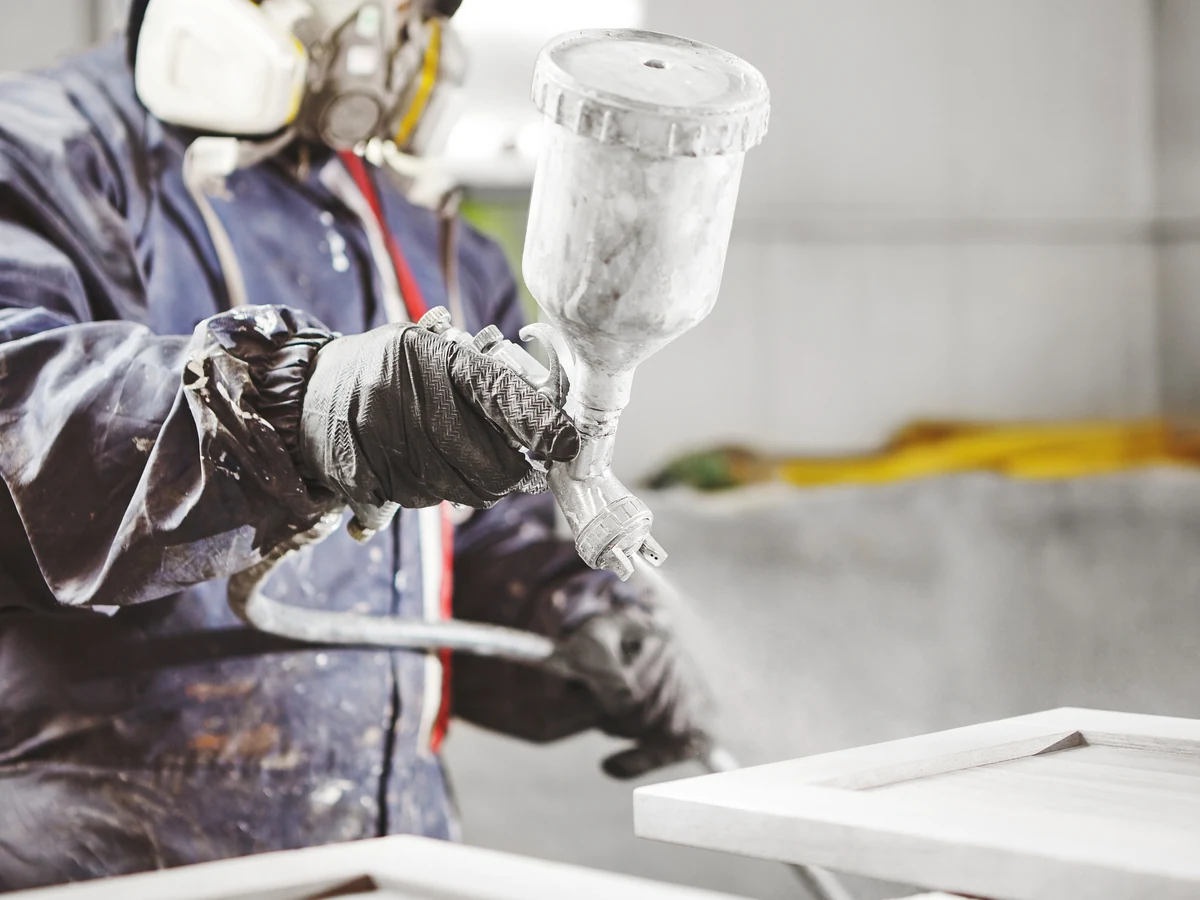 Painter using a spray gun for commercial decorating work in Odd Down Bath